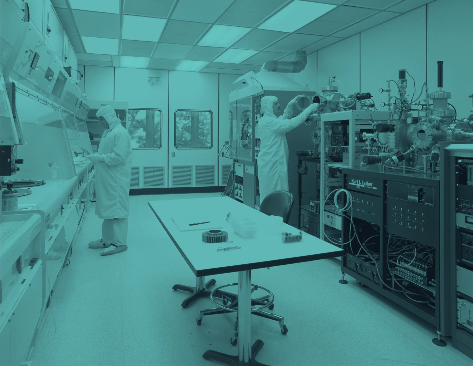 Engineers in cleanroom suits operating semiconductor fabrication equipment